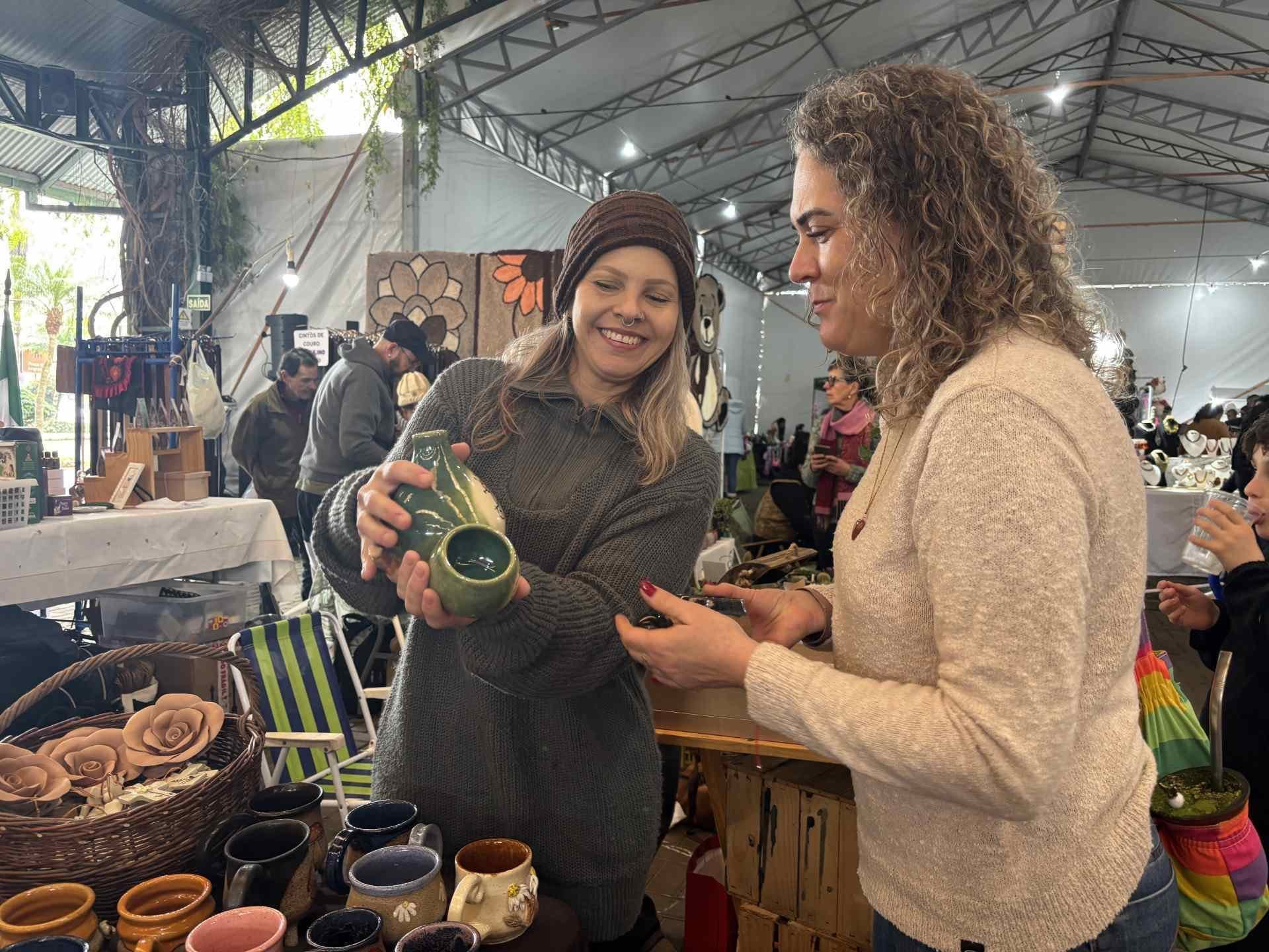 Nosso estande na XXV Feira Estadual do Artesanato: visitante conhecendo uma moringa em esmalte verde