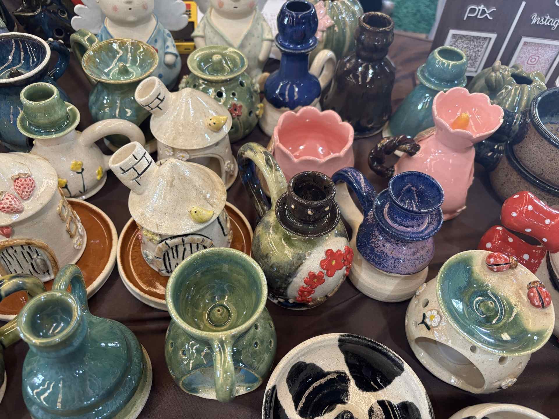Mesa do nosso estande na feira: casinhas de passarinho, moringas e vasos esmaltados feitos à mão